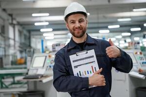 Happy with ,results, holding ,graphs. Factory worker is indoors with hard hat photo