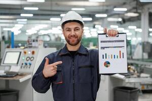 Plan with ,graphs ,,in hand. Factory worker is indoors with hard hat photo