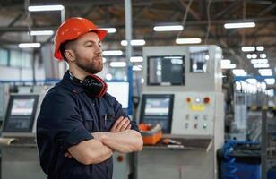 Confident, facial expression. Factory worker is indoors with hard hat photo