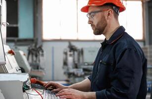 Operating the machine. Factory ,worker ,,is indoors with hard hat photo