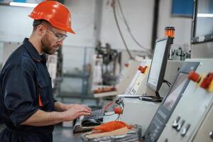Side ,view, operating ,,the machine. Factory worker is indoors with hard hat photo