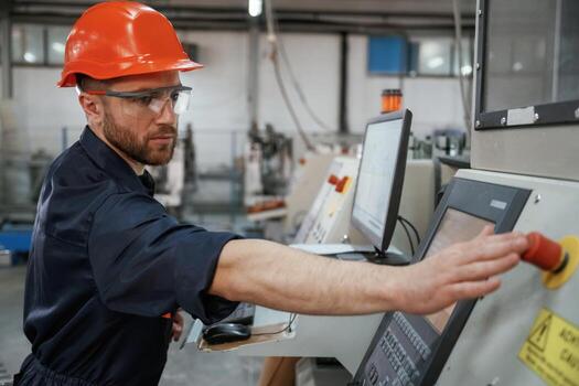 View from the side, working with machine,,, operator. Factory worker is indoors with hard hat photo