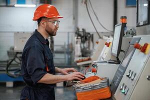 Operating, the machine,. Factory worker is indoors with hard hat photo