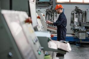 View ,from the side,, working with machine, operator. Factory worker is indoors with hard hat photo
