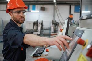 Side, view, operating ,,the machine. Factory worker is indoors with hard hat photo