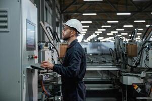 Using ,equipment,, operator. Factory worker is indoors with hard hat photo