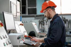Operating, the ,machine. Factory worker is indoors with hard hat photo