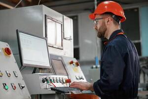 Operating, the, machine. Factory worker is indoors with hard hat photo