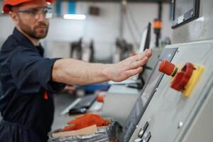 Side view, operating, the, machine. Factory worker is indoors with hard hat photo