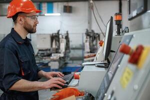 Side ,view, operating the machine. Factory worker is indoors with hard hat photo