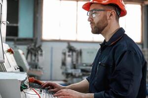 Operating the machine.. Factory worker is indoors with hard hat photo