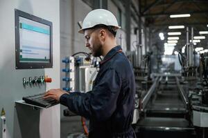 Adjusting settings ,of machine, operating. Factory worker is indoors with hard hat photo