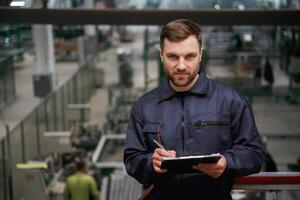 Writing information, into the notepad. Factory worker is indoors with hard hat photo
