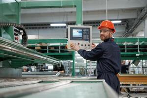 Adjusting settings, of machine, operating. Factory worker is indoors with hard hat photo