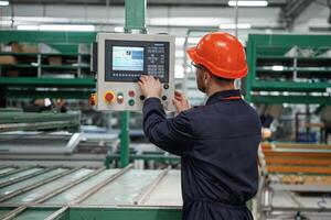 Adjusting settings of,machine, operating. Factory worker is indoors with hard hat photo