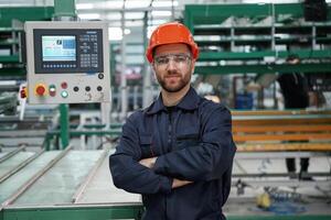 Beautiful man, is, standing with arms crossed. Factory worker is indoors with hard hat photo