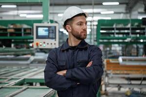 Against machine. .Factory worker is indoors with hard hat photo