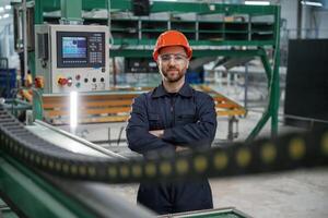 Beautiful ,man is standing with arms crossed. Factory worker is indoors with hard hat photo