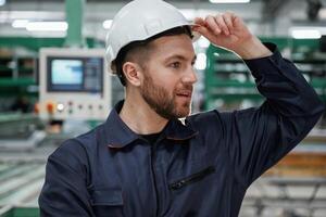 In white ,hard hat. Factory worker is indoors photo