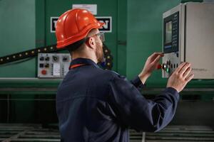 Green, colored machine, operator is busy. Factory worker is indoors with hard hat photo