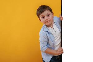 With huge smartphone,, copy space place. Little boy is in the studio against yellow background photo
