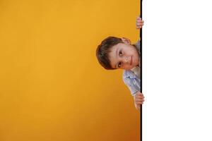 With huge smartphone, copy space ,place. Little boy is in the studio against yellow background photo