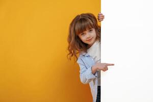 Hiding behind yellow background ,for copy space. Cute little girl is in the studio photo