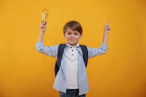 Light ,bulb in,hand. Conception of smart person and idea. Little boy is in the studio against yellow background photo
