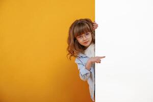 Hiding behind, yellow background for copy space. Cute little girl is in the studio photo