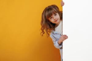 Hiding, behind yellow background for copy space. Cute little girl is in the studio photo