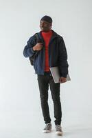 Silver colored laptop in hand.. Black ,man, in cap is in the studio against white background photo