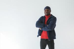 Posing with arms crossed. Black man,,, in ,cap is in the studio against white background photo