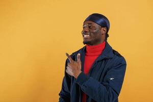Pointing by the, finger ,to ,copy space. Handsome black man is in the studio against yellow background photo