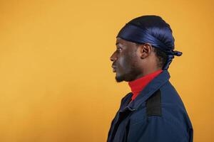 View from the side. Handsome black man is in the studio against yellow background photo