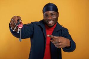 Keys for new home in hand, happy... Handsome black man is in the studio against yellow background photo