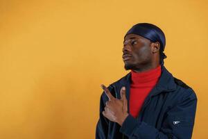 Pointing by the finger to, copy, space. Handsome black man is in the studio against yellow background photo
