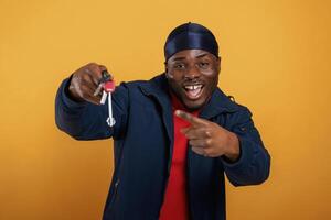 Keys for new home, in hand, happy. Handsome black man is in the studio against yellow background photo
