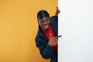 White copy, space, smiling and hiding behind it. Handsome black man is in the studio against yellow background photo