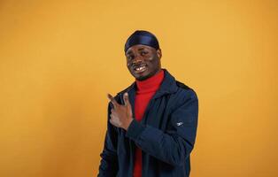 Pointing by ,the finger to copy space. Handsome black man is in the studio against yellow background photo