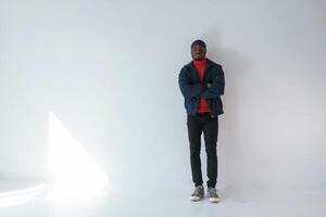 Posing with ,arms crossed. Black man in cap is in the studio against white background photo
