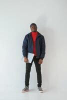 Silver colored, laptop in hand. Black man in cap is in the studio against white background photo