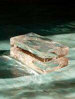 Two clear blocks stacked on top of each other with light reflecting off the surface photo