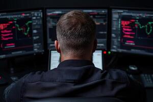 A man works at a computer station with multiple monitors displaying financial data photo
