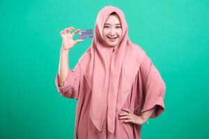Smiling woman holds debit card in front of her face with excitem photo
