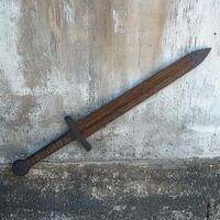 Weathered medieval sword resting against a concrete wall photo