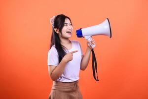 Young woman holding a megaphone and pointing with her index finger isolated on an orange background photo
