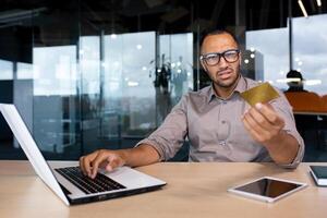 Businessman inside office trying to make a purchase in an online store, the man received an error in the transfer of funds for the order of the product, online fraud, disappointed looking at camera. photo