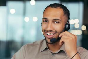 Portrait happy and smiling tech support worker with headset for call, african american man looking at camera closeup, working inside modern office call center, online customer support service. photo