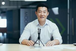 Portrait of successful business trainer coach, man smiling and looking at camera, businessman working in office, using professional microphone for online radio and podcast recording photo