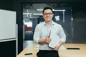Portrait of successful asian teacher in modern university office, man smiling and looking at camera photo